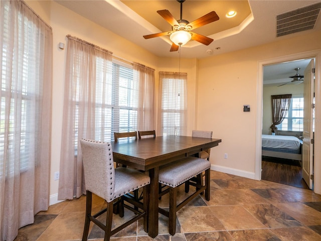 dining area featuring a raised ceiling and ceiling fan