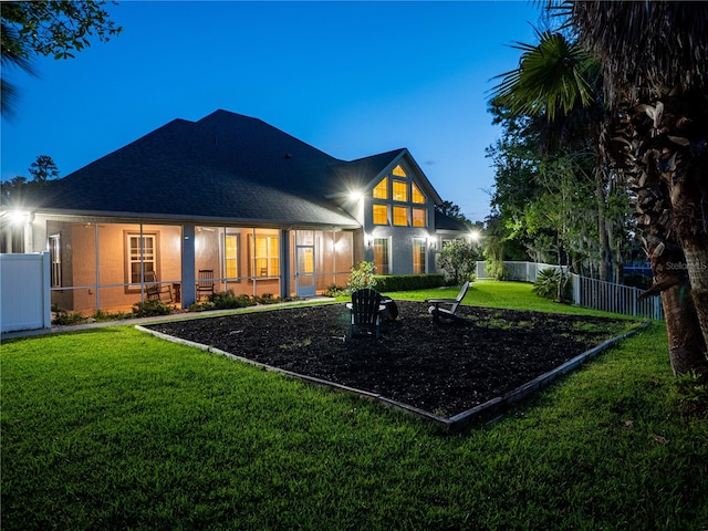 back house at dusk with a lawn