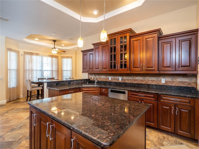 kitchen featuring sink, a raised ceiling, decorative backsplash, and a center island