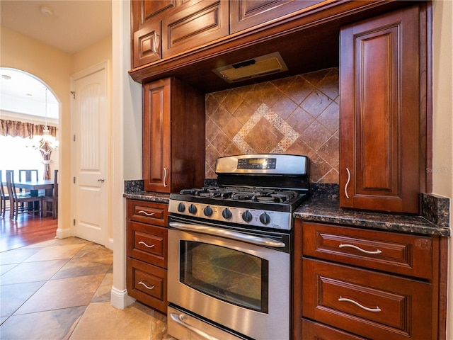 kitchen featuring dark stone countertops, tasteful backsplash, stainless steel gas range, and light tile patterned flooring