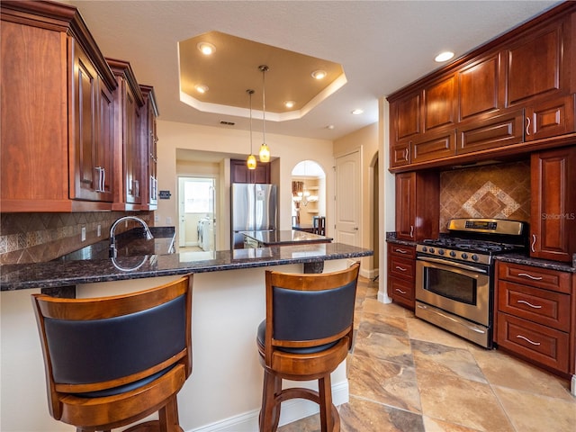 kitchen with kitchen peninsula, decorative backsplash, appliances with stainless steel finishes, a breakfast bar, and dark stone counters