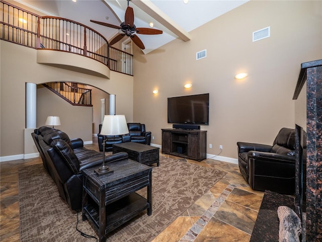 living room featuring ceiling fan, beamed ceiling, and a high ceiling