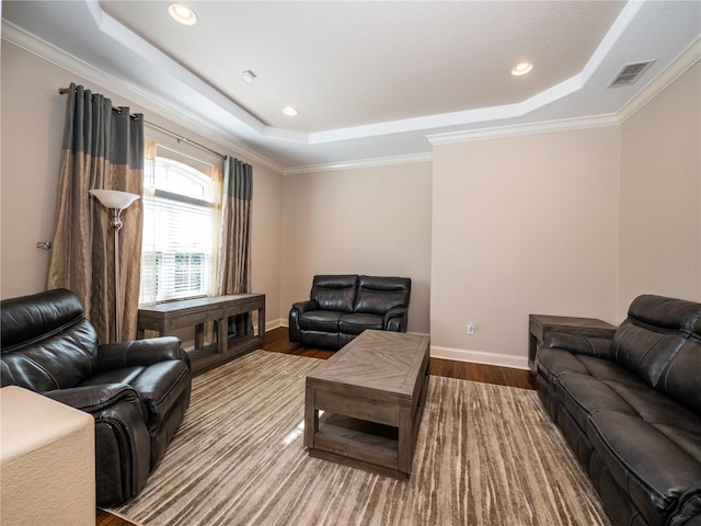 living room with crown molding, hardwood / wood-style flooring, and a tray ceiling