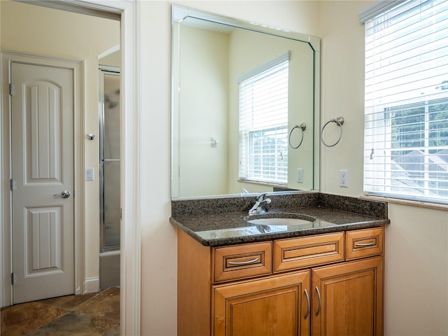 bathroom featuring a wealth of natural light, vanity, and enclosed tub / shower combo