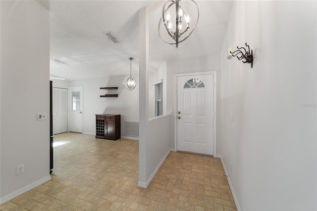 hall featuring a textured ceiling and a notable chandelier