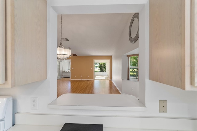 kitchen with wood-type flooring, light brown cabinets, and an inviting chandelier