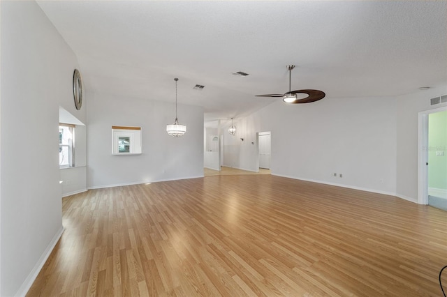 unfurnished living room featuring ceiling fan with notable chandelier, light hardwood / wood-style flooring, and high vaulted ceiling