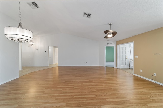 spare room featuring light hardwood / wood-style flooring, a notable chandelier, and lofted ceiling