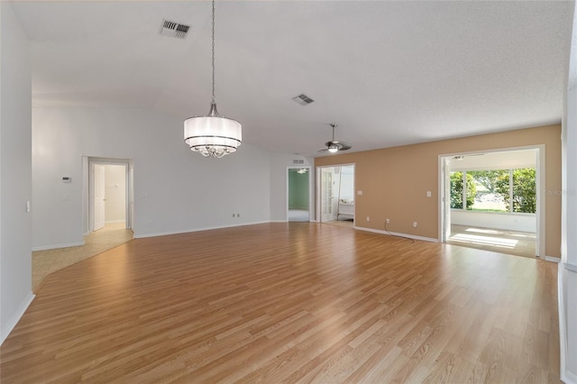 empty room with lofted ceiling, light hardwood / wood-style flooring, and ceiling fan with notable chandelier