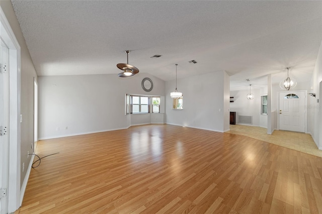 unfurnished living room with light hardwood / wood-style flooring, a textured ceiling, and lofted ceiling