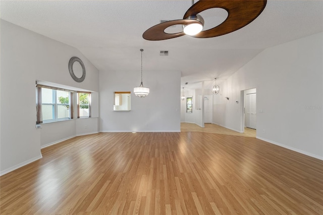 empty room featuring lofted ceiling, light hardwood / wood-style floors, and an inviting chandelier