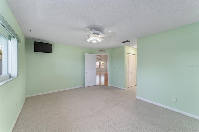 empty room with a textured ceiling, ceiling fan, and carpet floors