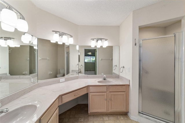 bathroom with tile flooring, dual vanity, a textured ceiling, an enclosed shower, and toilet