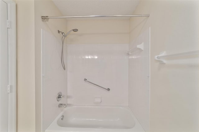 bathroom with a textured ceiling and tiled shower / bath