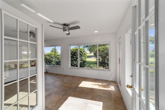 unfurnished sunroom with ceiling fan