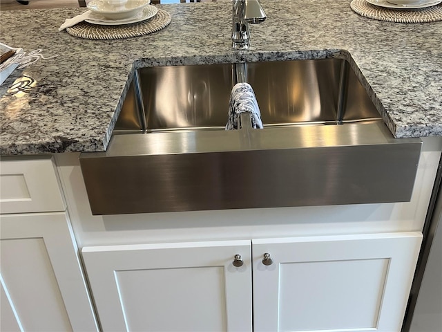 details with white cabinets, stone countertops, and sink