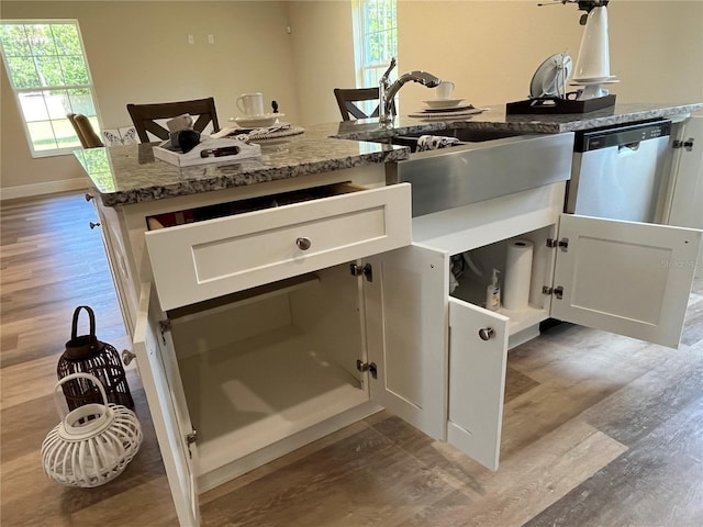 interior space featuring sink, white cabinetry, light hardwood / wood-style floors, stainless steel dishwasher, and dark stone counters