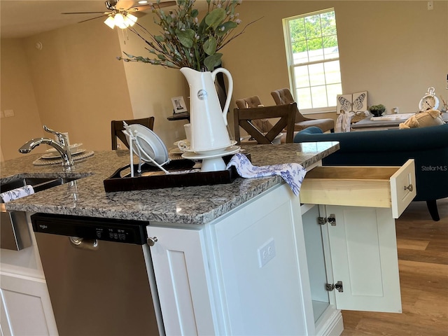 kitchen with light hardwood / wood-style floors, white cabinets, dishwasher, and light stone countertops