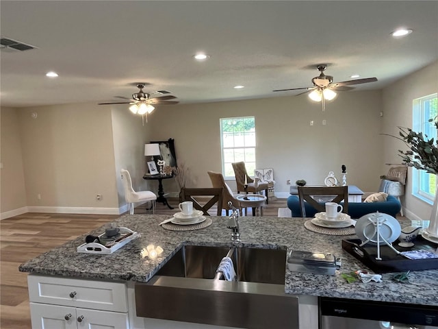 kitchen featuring light stone countertops, dishwasher, hardwood / wood-style floors, white cabinets, and sink