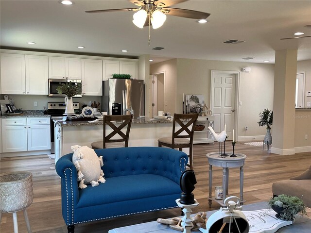 living room with ceiling fan and light hardwood / wood-style flooring