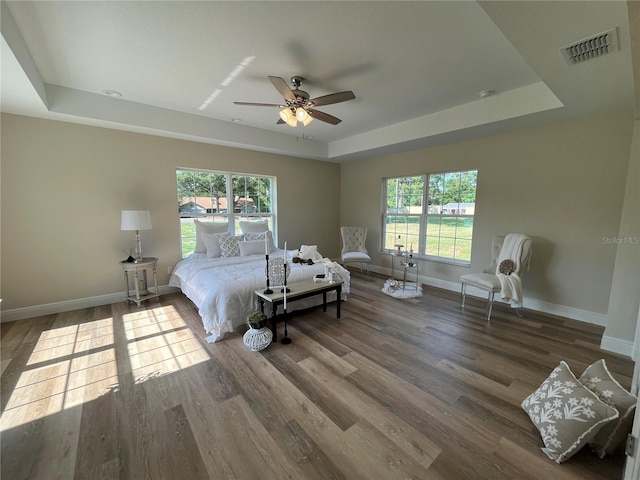 bedroom featuring wood-type flooring, ceiling fan, and a tray ceiling