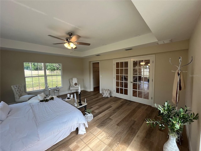 bedroom with french doors, hardwood / wood-style flooring, ceiling fan, and a tray ceiling