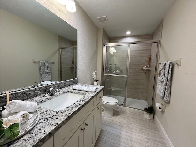 bathroom with a textured ceiling, an enclosed shower, vanity, and toilet