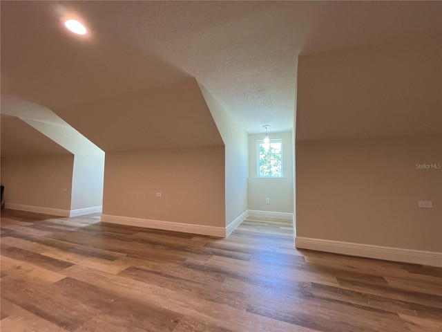 bonus room with a textured ceiling and hardwood / wood-style floors