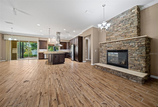 unfurnished living room with a notable chandelier, crown molding, light wood-type flooring, and a fireplace