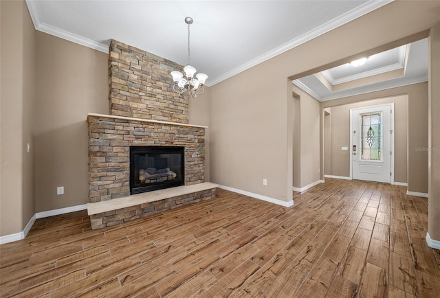 unfurnished living room with a fireplace, hardwood / wood-style floors, an inviting chandelier, and ornamental molding