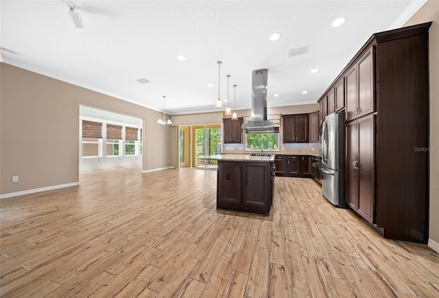 kitchen featuring island exhaust hood, stainless steel fridge, decorative light fixtures, light hardwood / wood-style flooring, and a center island