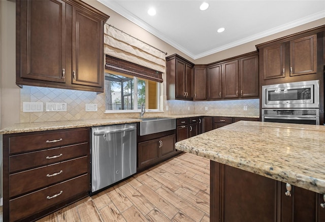 kitchen with crown molding, light stone countertops, light wood-type flooring, and appliances with stainless steel finishes