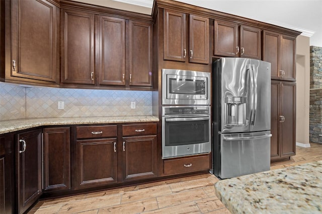 kitchen featuring tasteful backsplash, light stone counters, light wood-type flooring, and appliances with stainless steel finishes