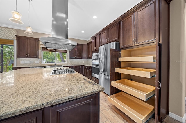 kitchen with island exhaust hood, appliances with stainless steel finishes, light stone countertops, and a healthy amount of sunlight