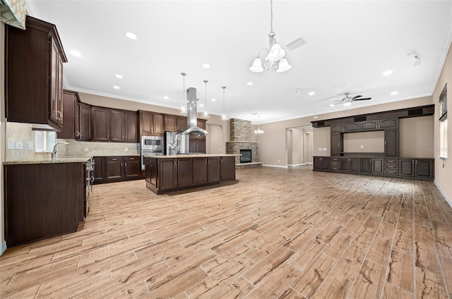 kitchen with pendant lighting, dark brown cabinets, stainless steel appliances, and light wood-type flooring