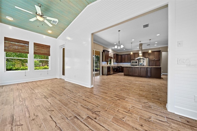 unfurnished living room with ceiling fan with notable chandelier, light hardwood / wood-style floors, and high vaulted ceiling