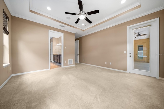 carpeted spare room featuring a tray ceiling, ceiling fan, and crown molding