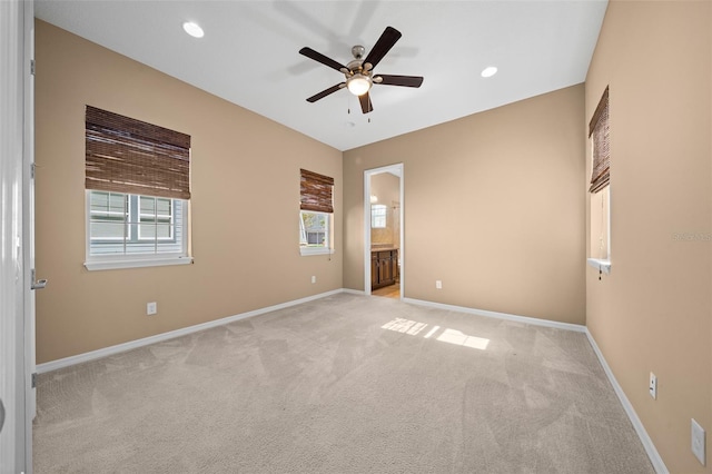 unfurnished bedroom featuring ceiling fan, light carpet, and ensuite bath