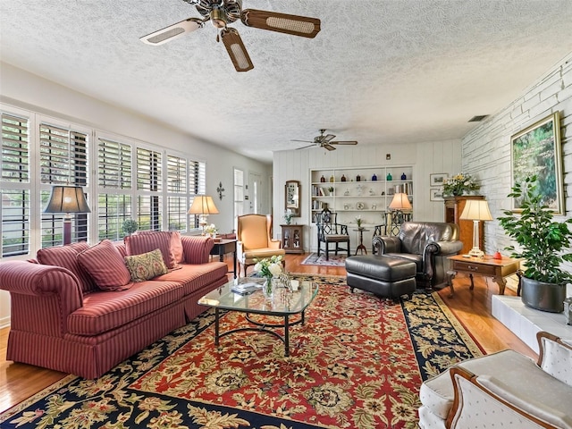 living room with a textured ceiling, hardwood / wood-style floors, and ceiling fan