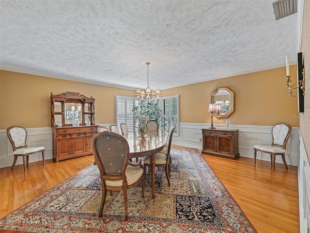 dining area featuring a textured ceiling, a notable chandelier, and light hardwood / wood-style floors