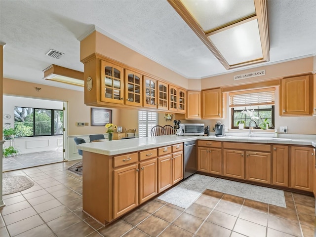 kitchen featuring appliances with stainless steel finishes, light tile floors, a textured ceiling, sink, and kitchen peninsula