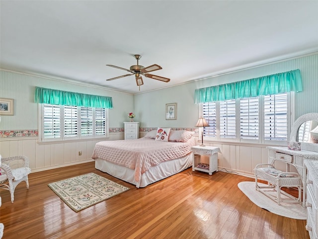 bedroom with hardwood / wood-style floors, ceiling fan, and ornamental molding