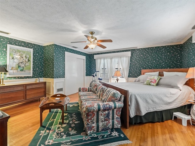 bedroom with ceiling fan, crown molding, hardwood / wood-style flooring, and a textured ceiling