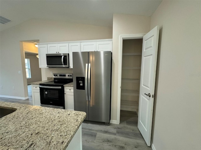 kitchen with light stone counters, white cabinetry, and appliances with stainless steel finishes