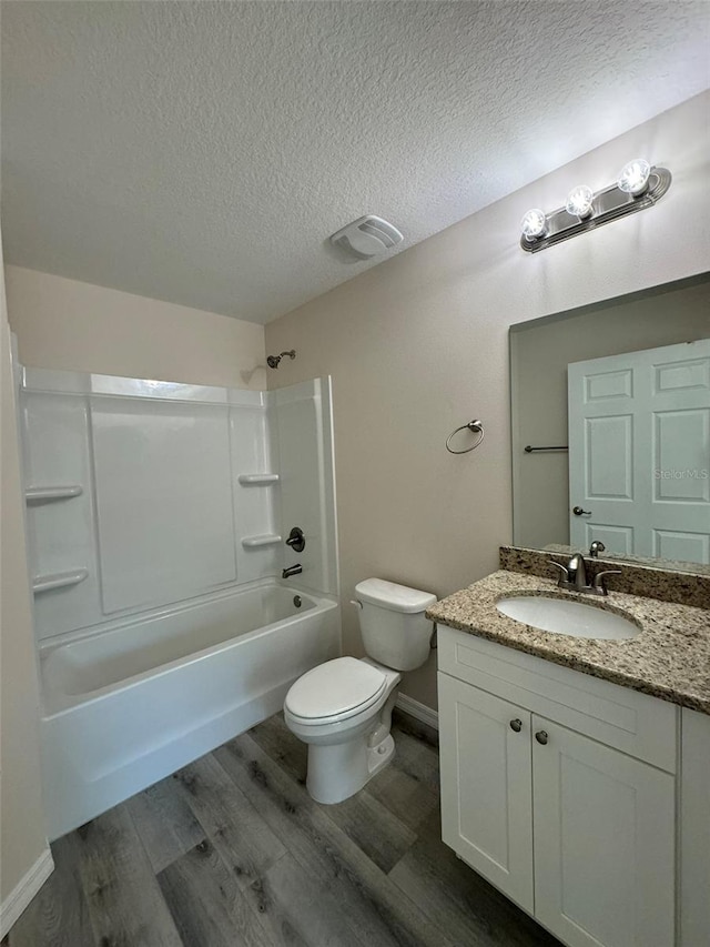 full bathroom featuring washtub / shower combination, hardwood / wood-style floors, a textured ceiling, toilet, and vanity