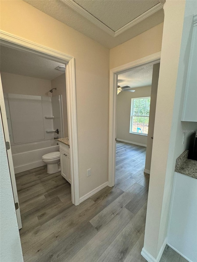 full bathroom with shower / bathtub combination, vanity, a textured ceiling, wood-type flooring, and toilet