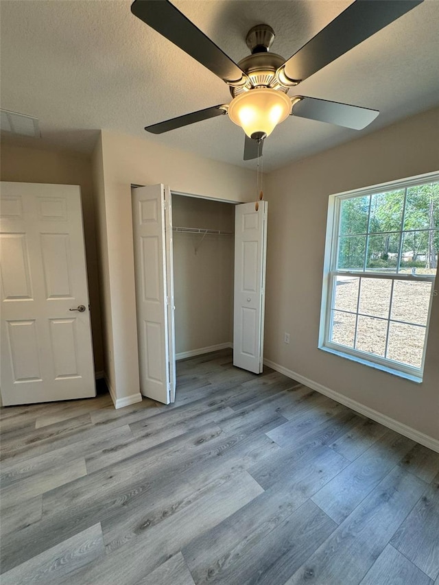 unfurnished bedroom featuring a textured ceiling, light wood-type flooring, a closet, and ceiling fan