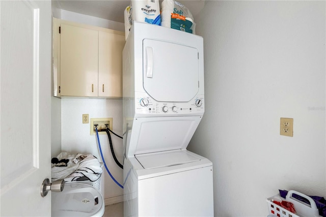 clothes washing area featuring cabinets, hookup for a washing machine, and stacked washer and dryer