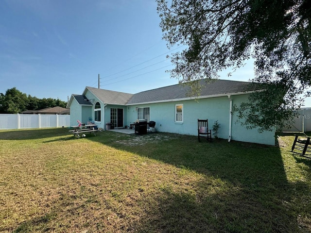 rear view of property featuring a lawn and a patio area