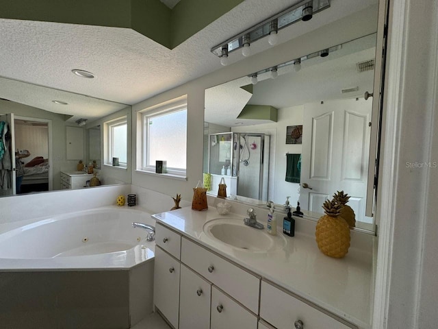 bathroom with vanity with extensive cabinet space, independent shower and bath, and a textured ceiling